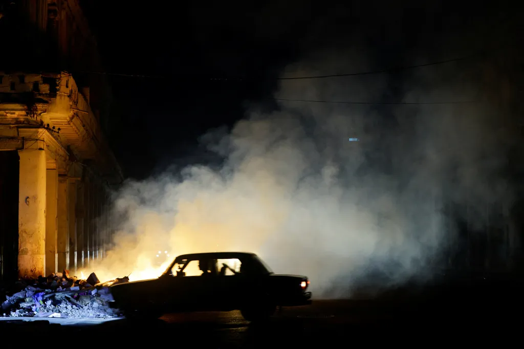 A car drives past a burning pile of garbage as Cuba's national power grid collapsed, marking the third major outage in nine days, in Havana, Cuba, July 14, 2026.