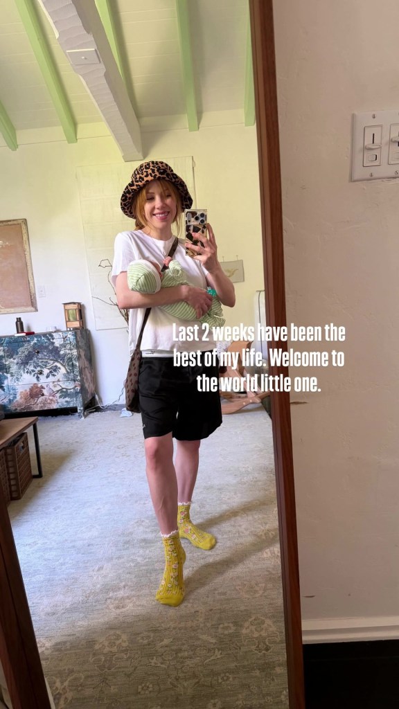 Carly Rae Jepsen holding her newborn baby while taking a mirror selfie.