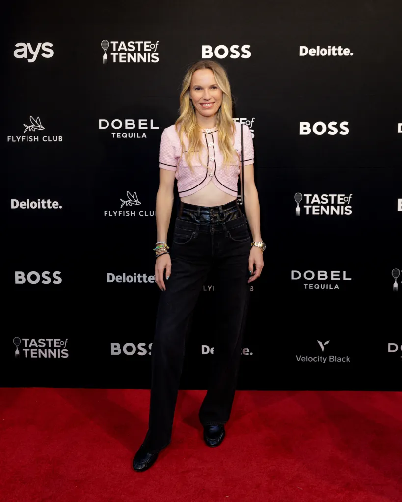 Caroline Wozniacki standing on a red carpet in front of a black background with sponsor logos.