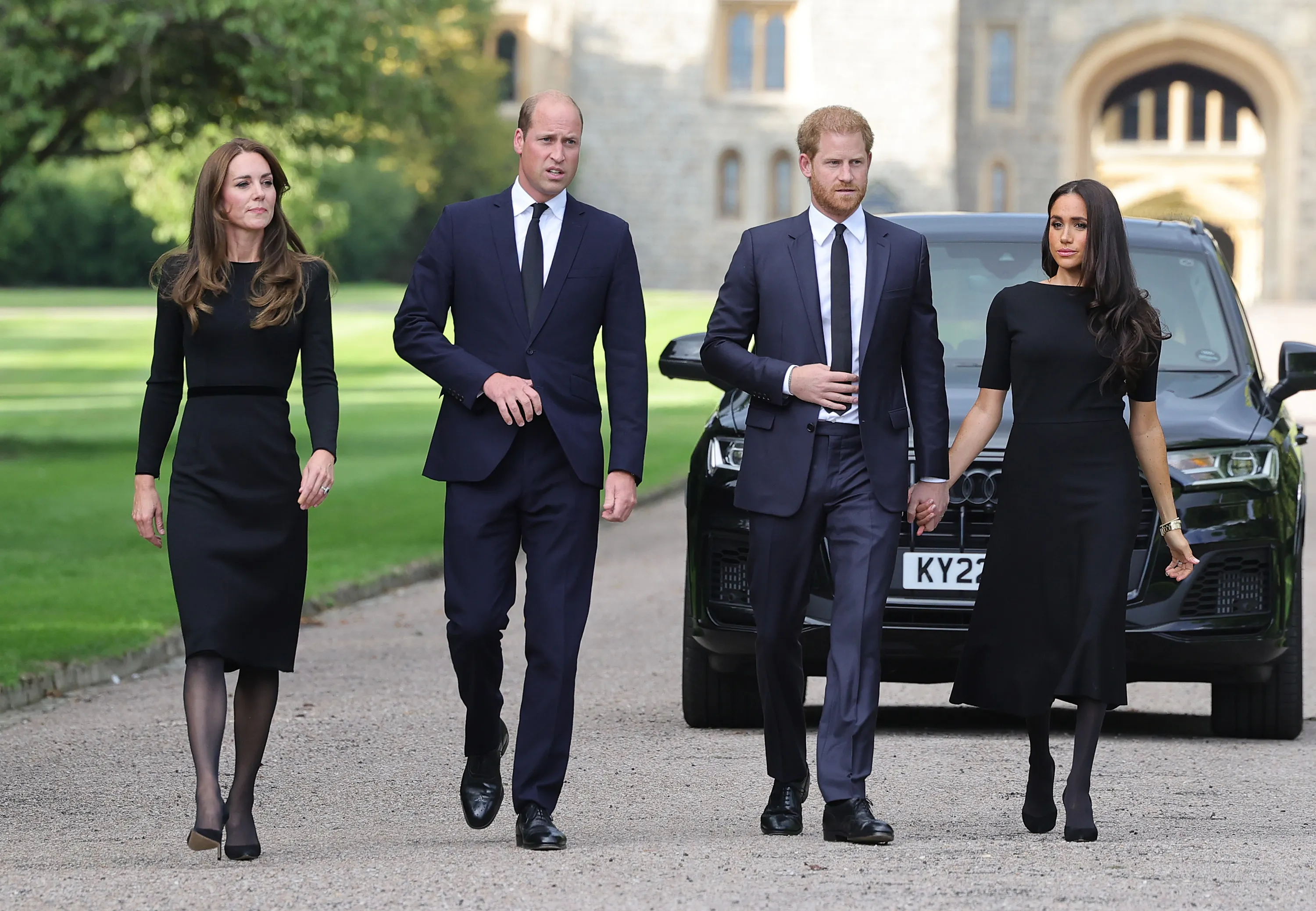Catherine, Princess of Wales, Prince William, Prince of Wales, Prince Harry, Duke of Sussex, and Meghan, Duchess of Sussex, walk together in front of Windsor Castle.