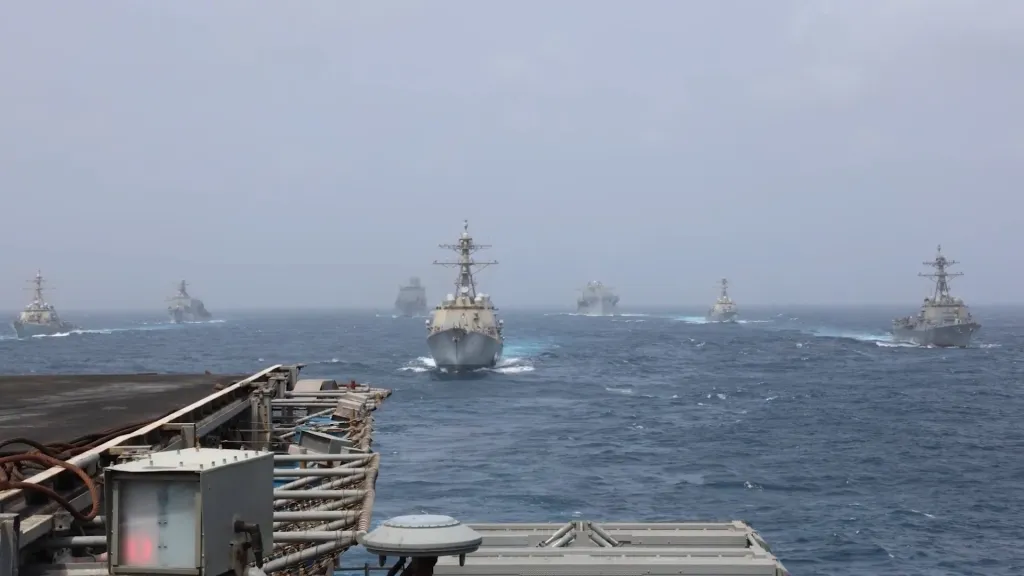 A fleet of seven warships moving through choppy waters.