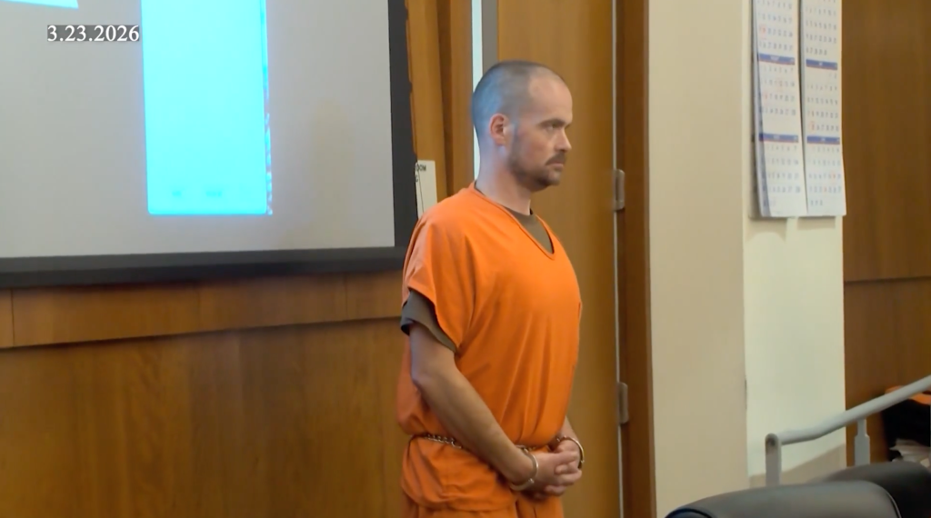 Christian Parmalee Edwards, wearing an orange jumpsuit and handcuffs, stands in court.