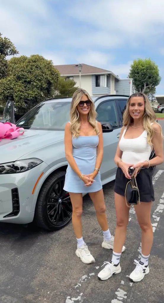 Christina Haack and Heather Rae Young posing in front of a new car.
