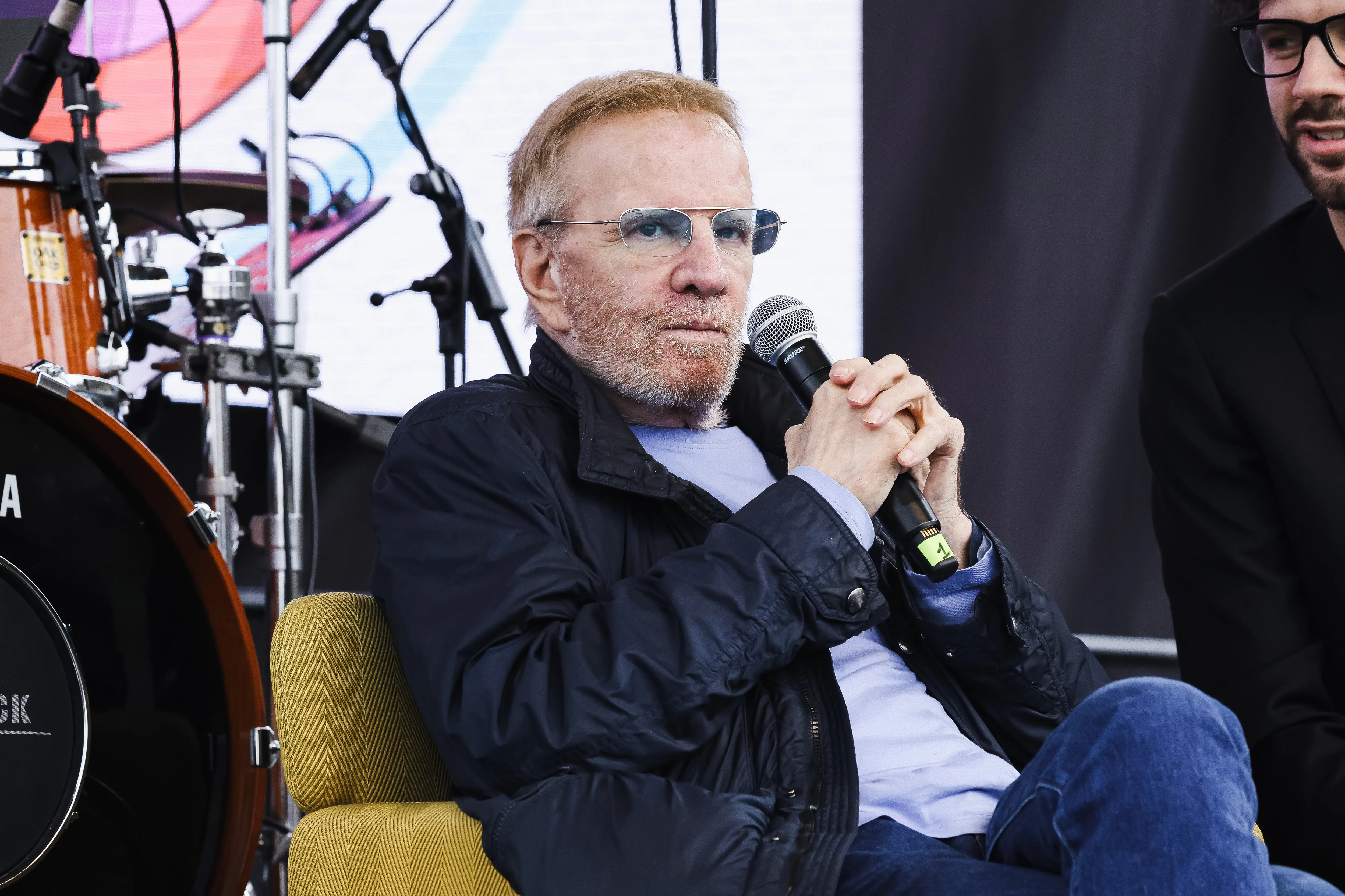 Christopher Lambert on stage for an interview, holding a microphone.