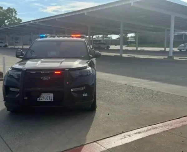 Police car with flashing lights in a parking lot.