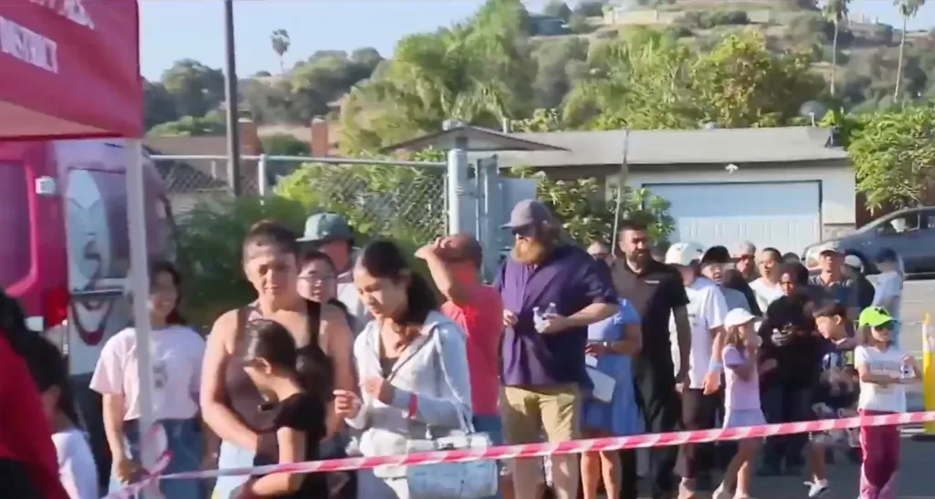 People line up for free backpacks and school supplies at a back-to-school event.