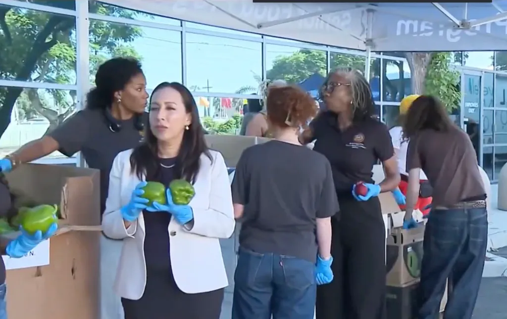 People wearing blue gloves handle produce at a back-to-school event.