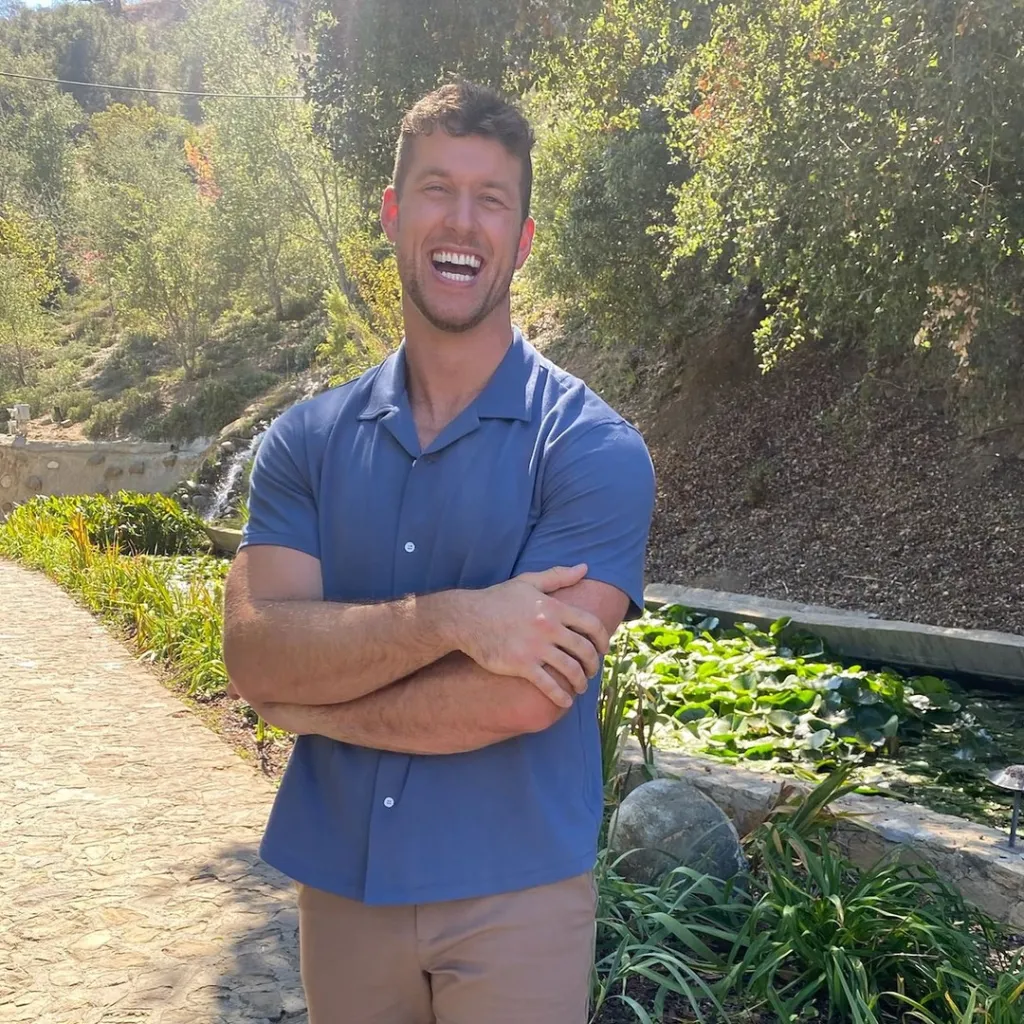 Clayton Echard smiling with his arms crossed in a garden.