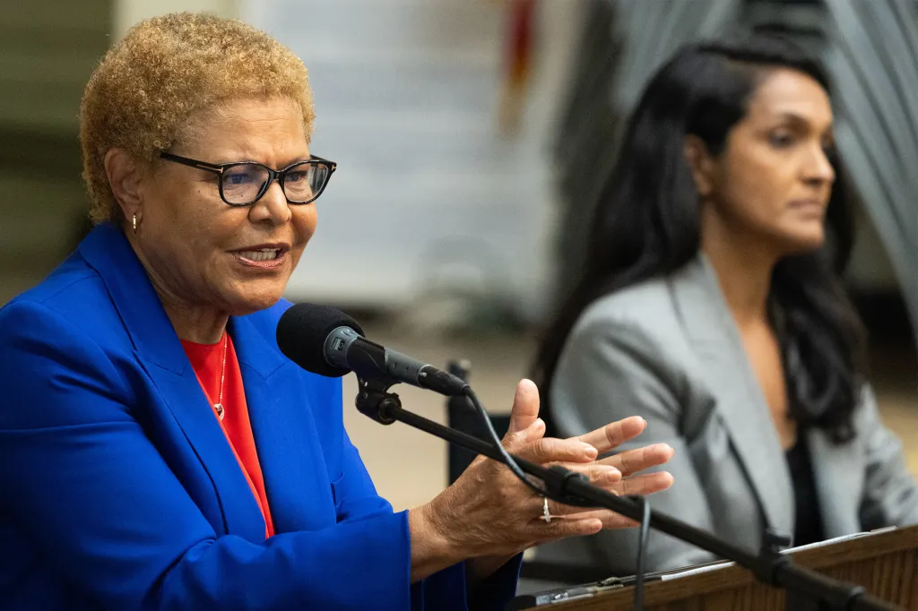 Karen Bass speaking at a mayoral debate, with another speaker out of focus in the background.