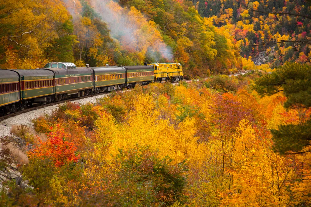 The Conway Scenic Railway train travels on the Crawford Notch route, just west of Bartlett, New Hampshire, as hardwood trees show peak fall color in the White Mountain National Forest.