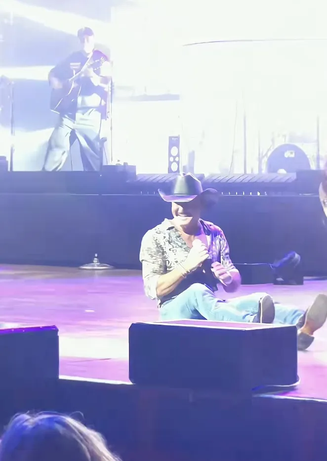 Country music legend Tim McGraw sitting on the stage after falling during a performance.