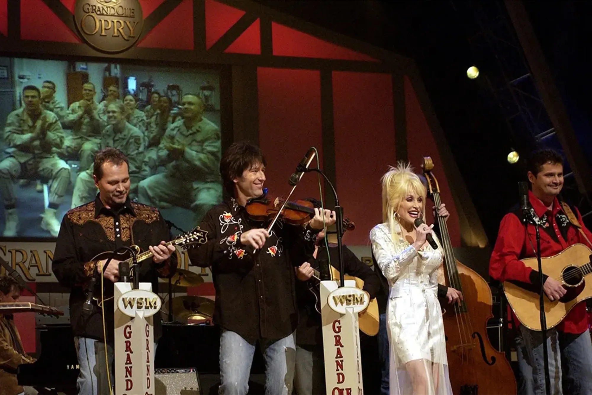 Parton sings on stage during a Grand Ole Opry live broadcast in Nashville, Tenn., as U.S. soldiers watch the show via a video feed in Iraq.
