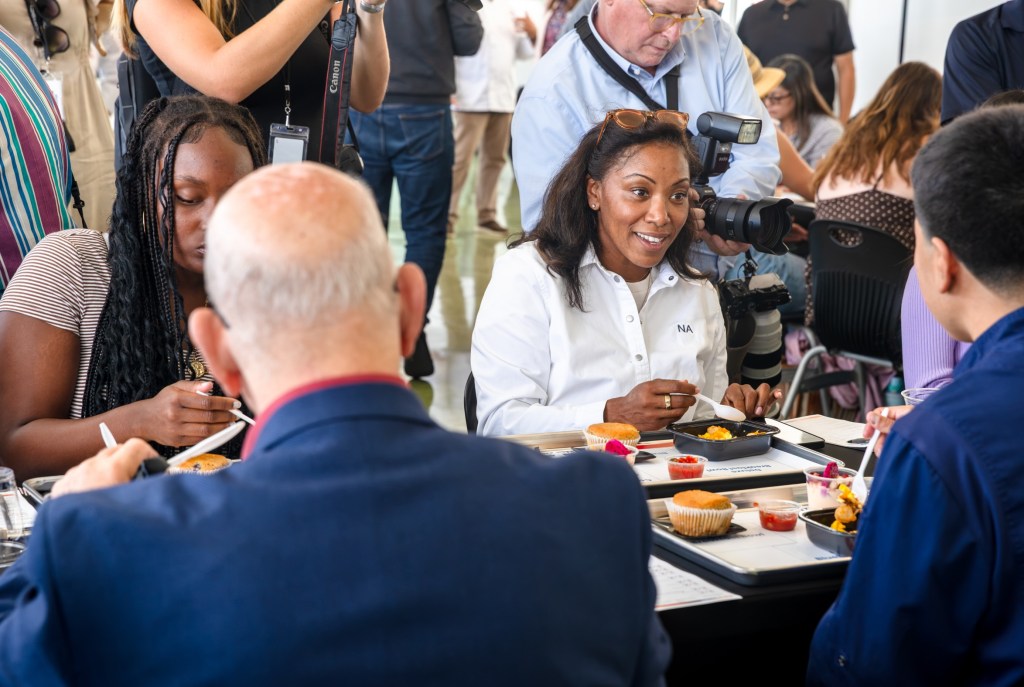 Adults and students tasting new school menu items.