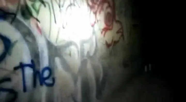 Dark tunnel walls covered in graffiti.
