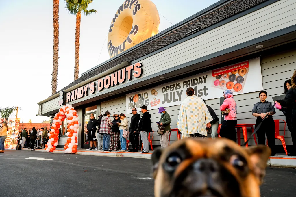 People gathered in front of the new Randy's Donuts in Santa Clara, with an inflatable donut on the roof.