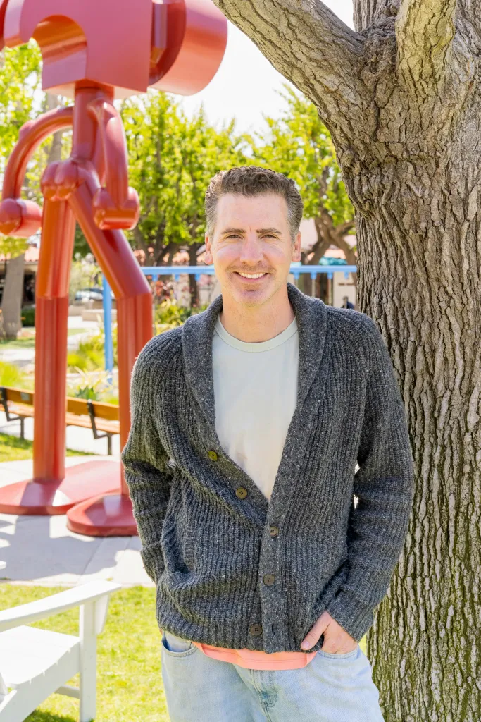 Daniel Smith, who is running for Malibu City Council, smiles while leaning against a tree.