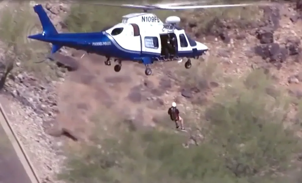 Helicopter airlifting a 72-year-old hiker from a mountainside.