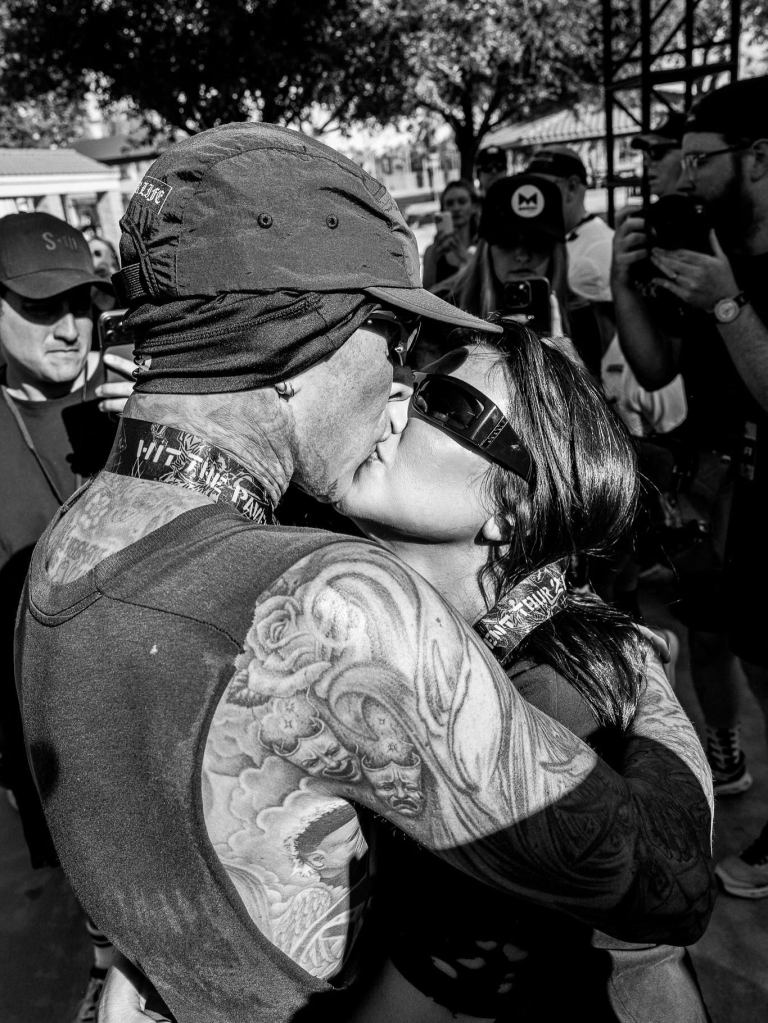 A black and white photo of Travis Barker and Kourtney Kardashian kissing.