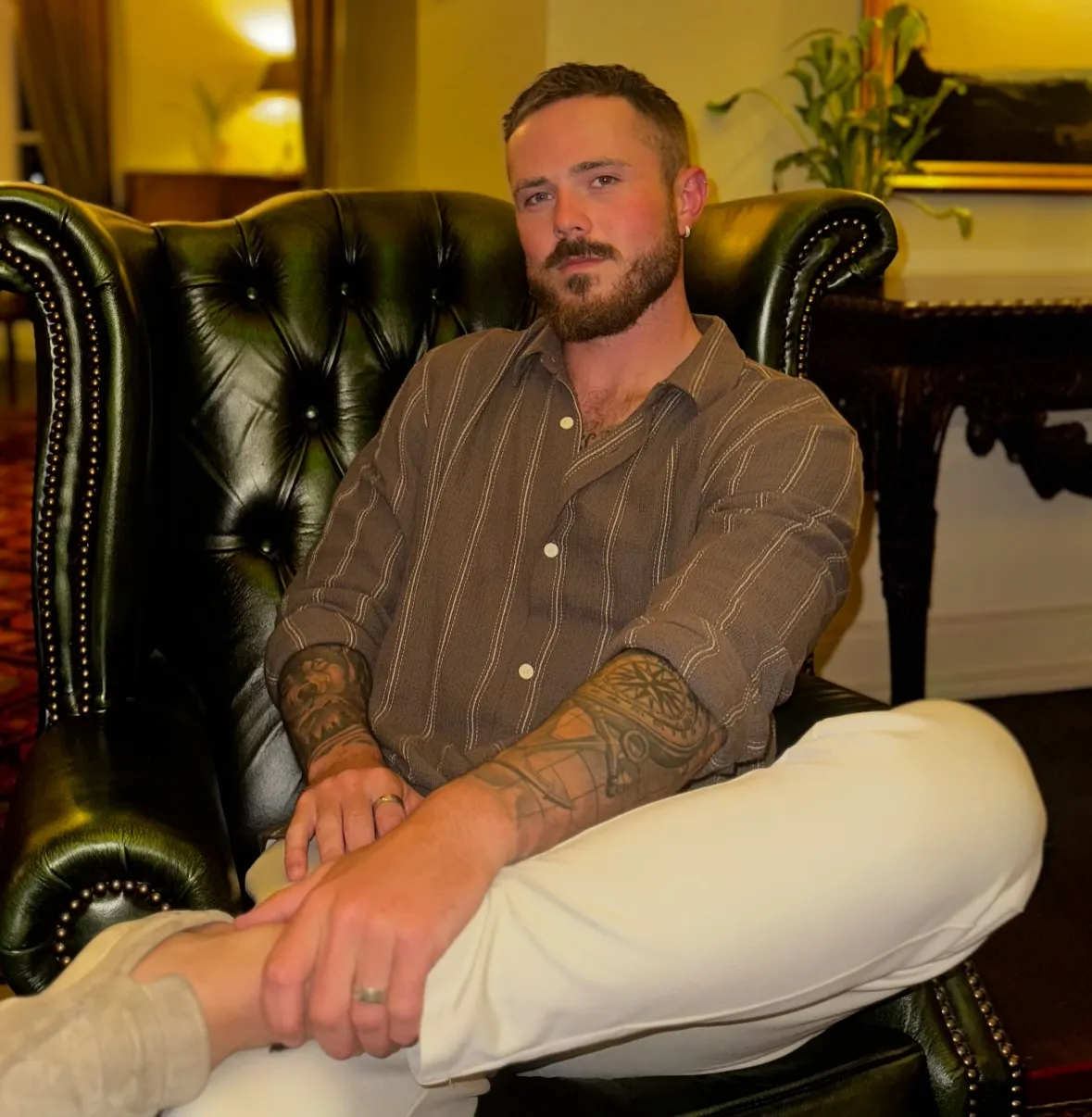 Nathan Gallagher sitting in a dark green leather armchair.