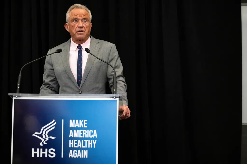 Robert F. Kennedy Jr. speaking at a podium with the HHS logo and