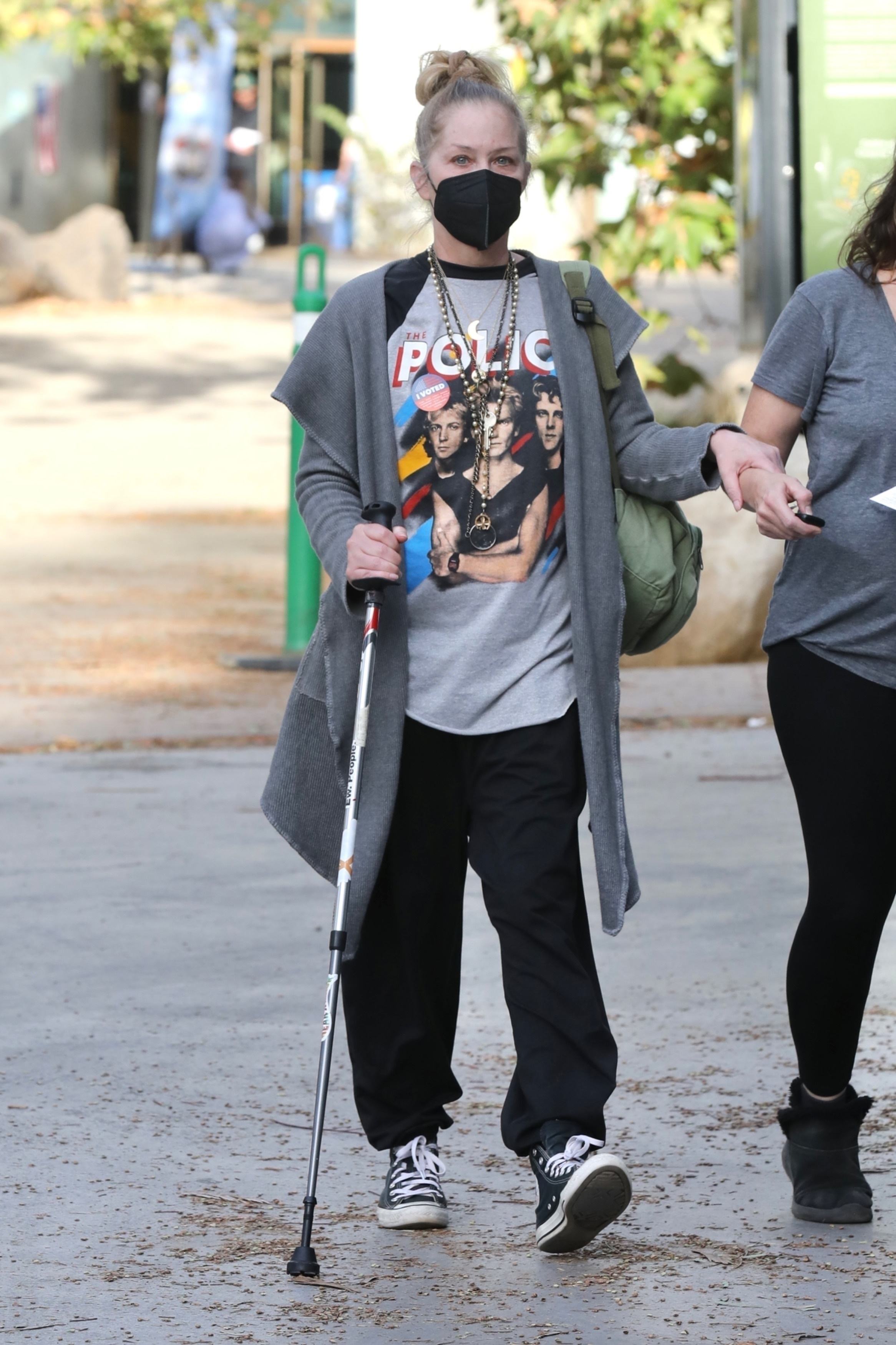 Christina Applegate, masked, walking with a cane and wearing an 