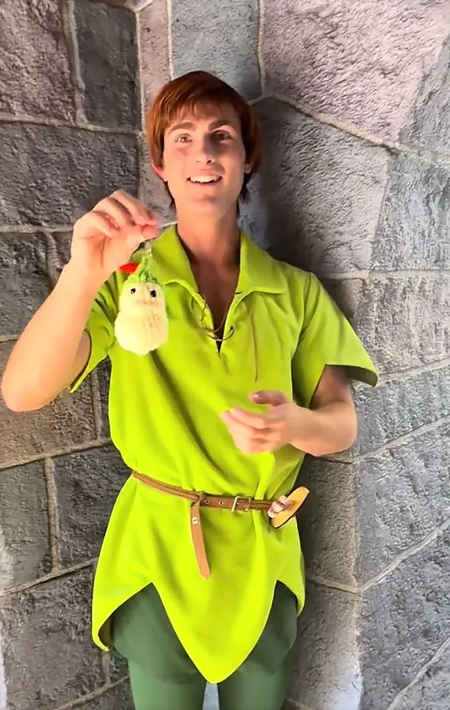 Toni dressed as Peter Pan and holding a small Peter Pan plushie.