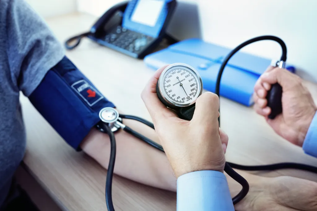 Doctor checking a patient's blood pressure with a manual sphygmomanometer.