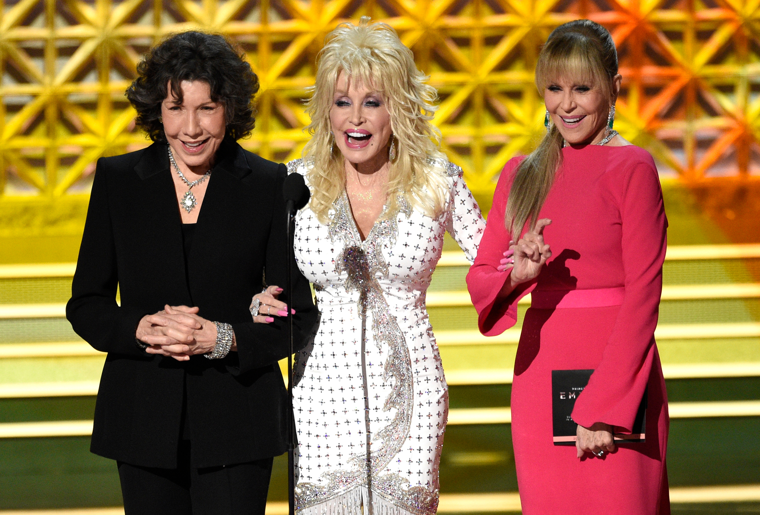 Dolly Parton, center, stands on stage with Lily Tomlin, left, and Jane Fonda.