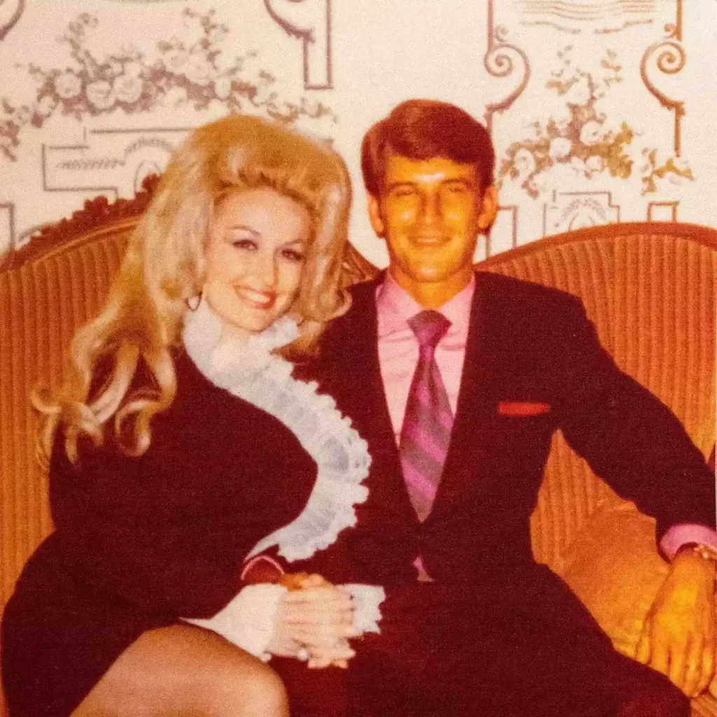 Dolly Parton and Carl Thomas Dean smiling on a couch.