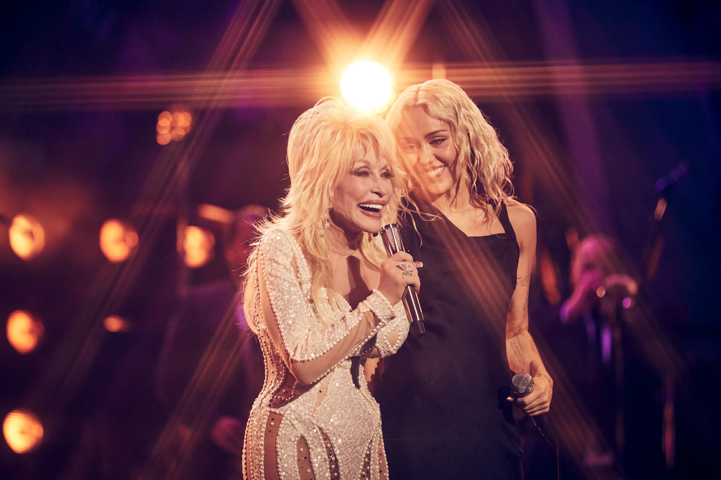 Dolly Parton and Miley Cyrus perform together on stage.
