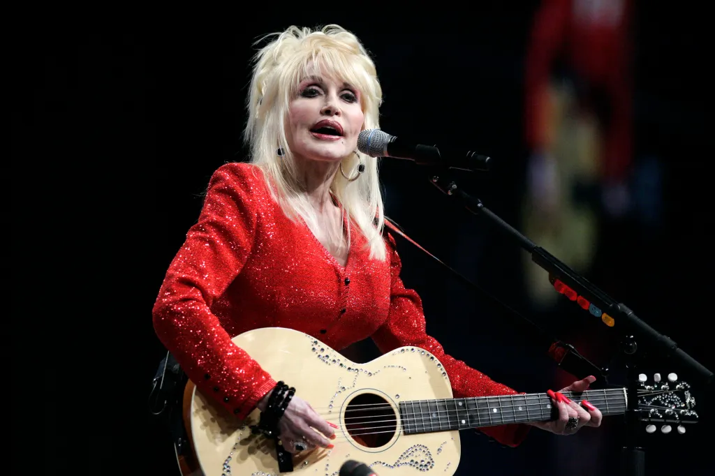 Dolly Parton performing with her acoustic guitar.