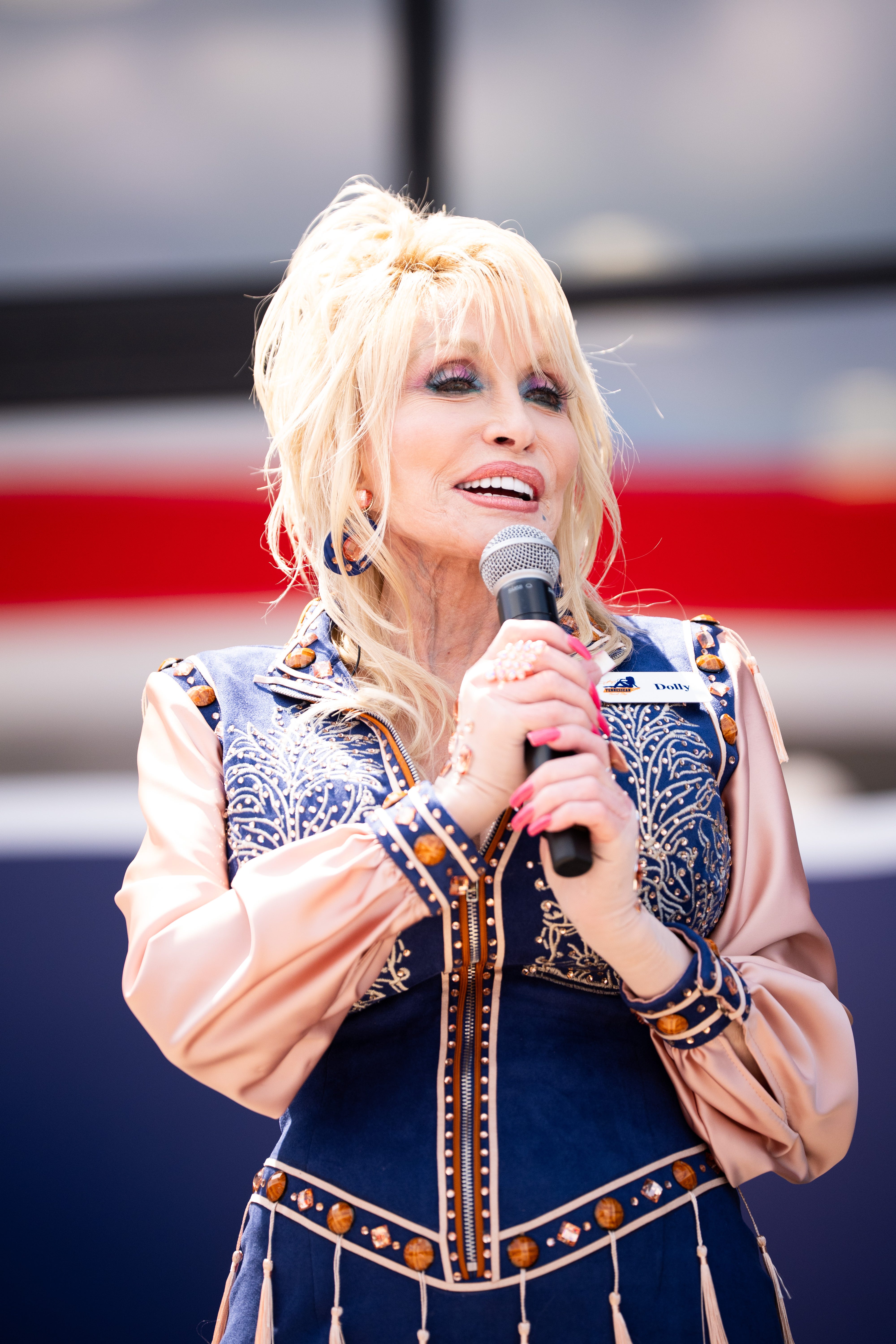 Dolly Parton speaks into a microphone at the grand opening of Dolly's Tennessean Travel Stop.