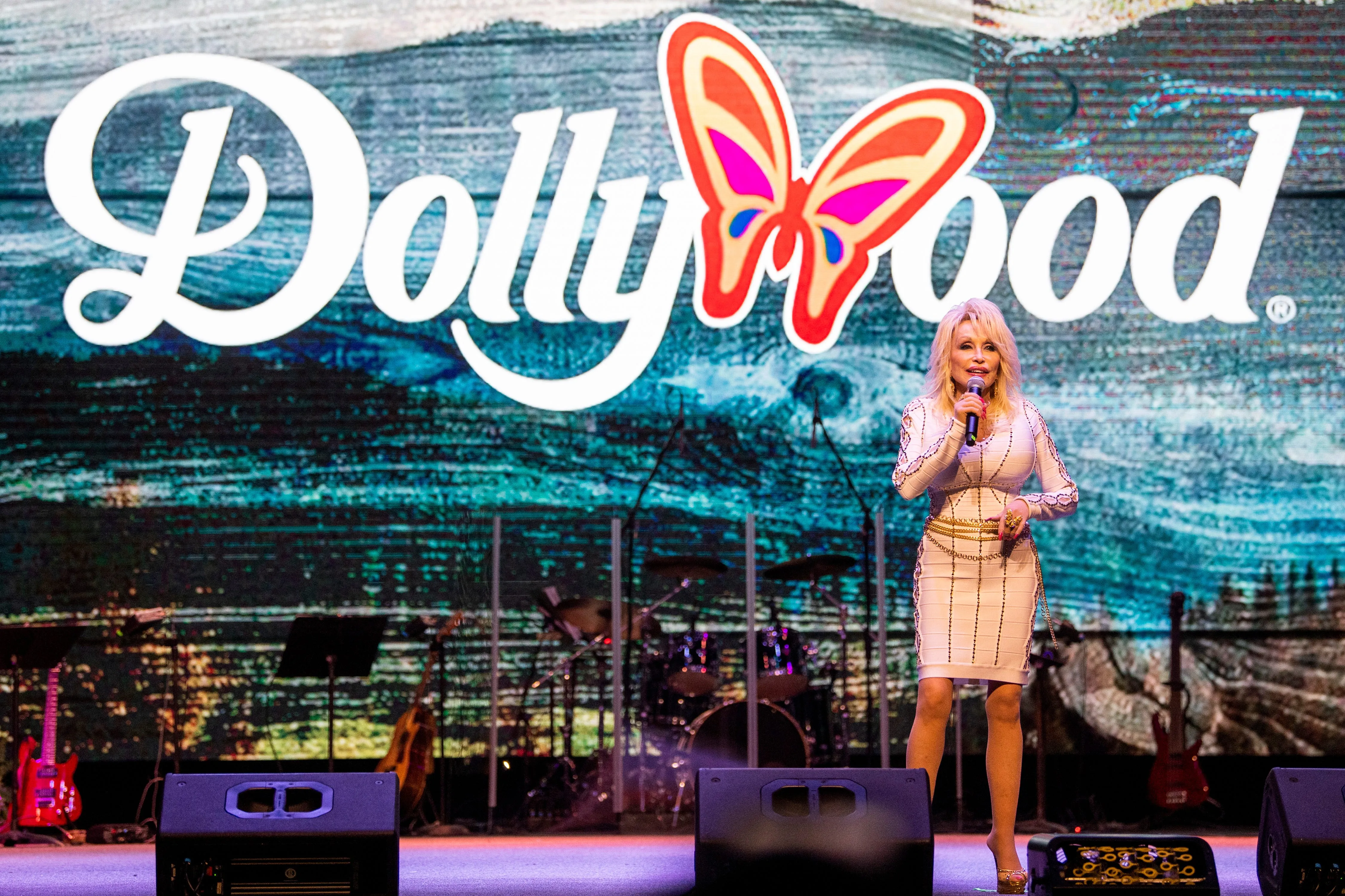 Dolly Parton speaking into a microphone on stage at Dollywood.