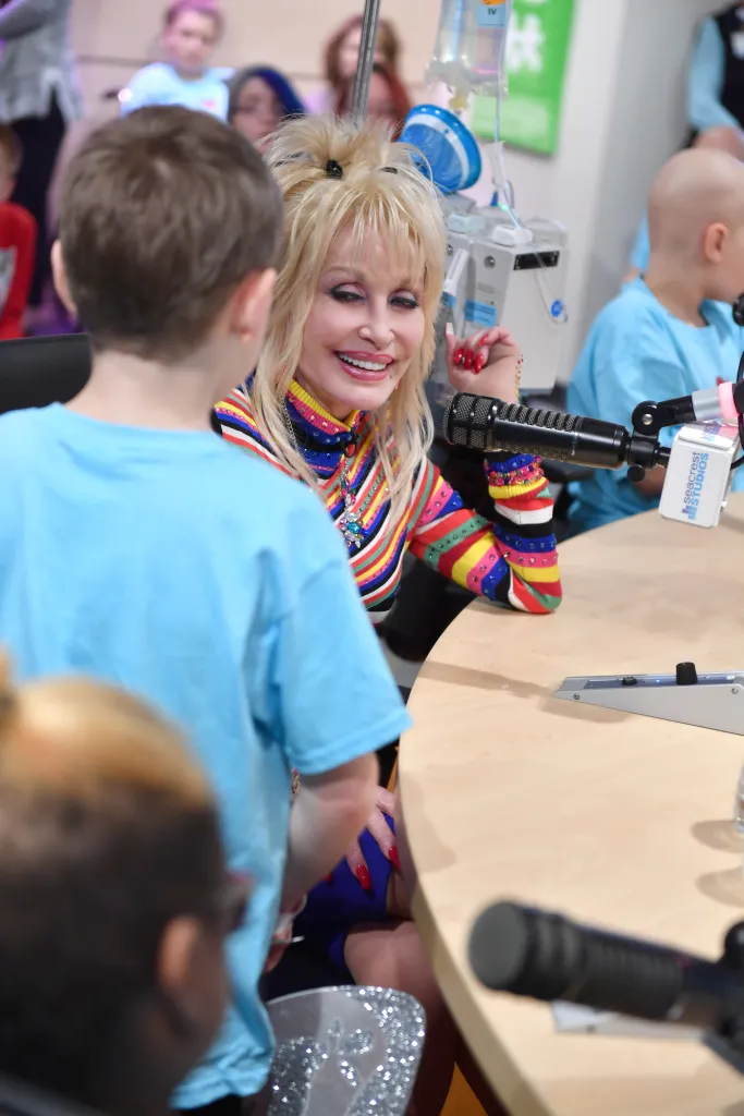 Dolly Parton smiling and talking to a child in a recording studio.