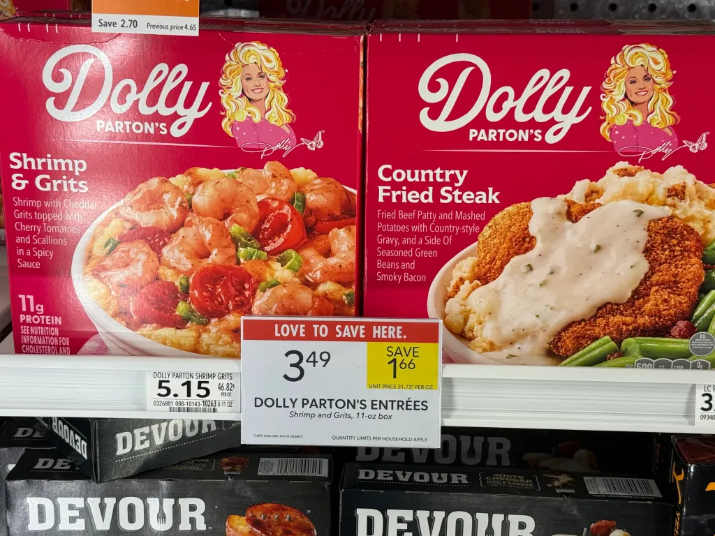 Dolly Parton's frozen Shrimp & Grits and Country Fried Steak food boxes in a freezer section at a Publix.