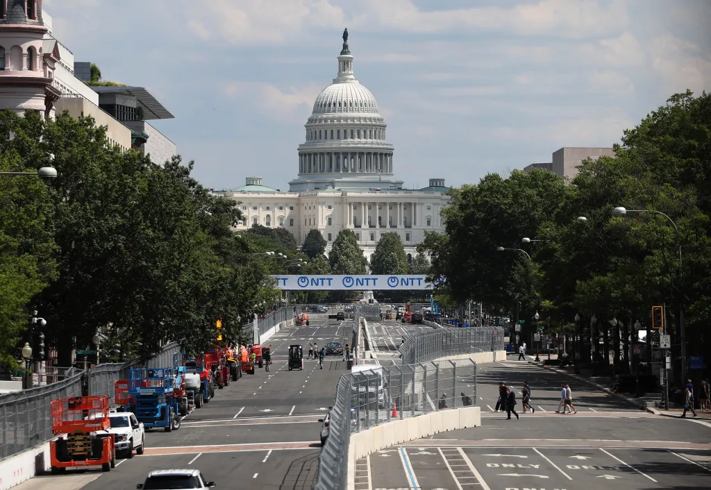 The U.S. Capitol Building dome overlooking Pennsylvania Avenue, which is set up as a race track with barriers, with a banner for the NTT INDYCAR Series overhead.
