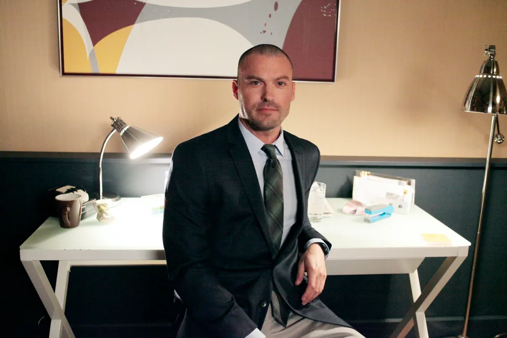 Brian Austin Green as Chris sitting at a desk.