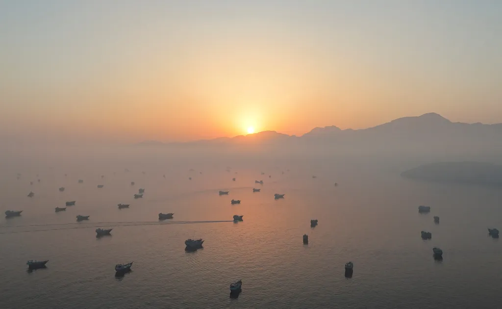 Drone view of many vessels in the Strait of Hormuz at sunrise.