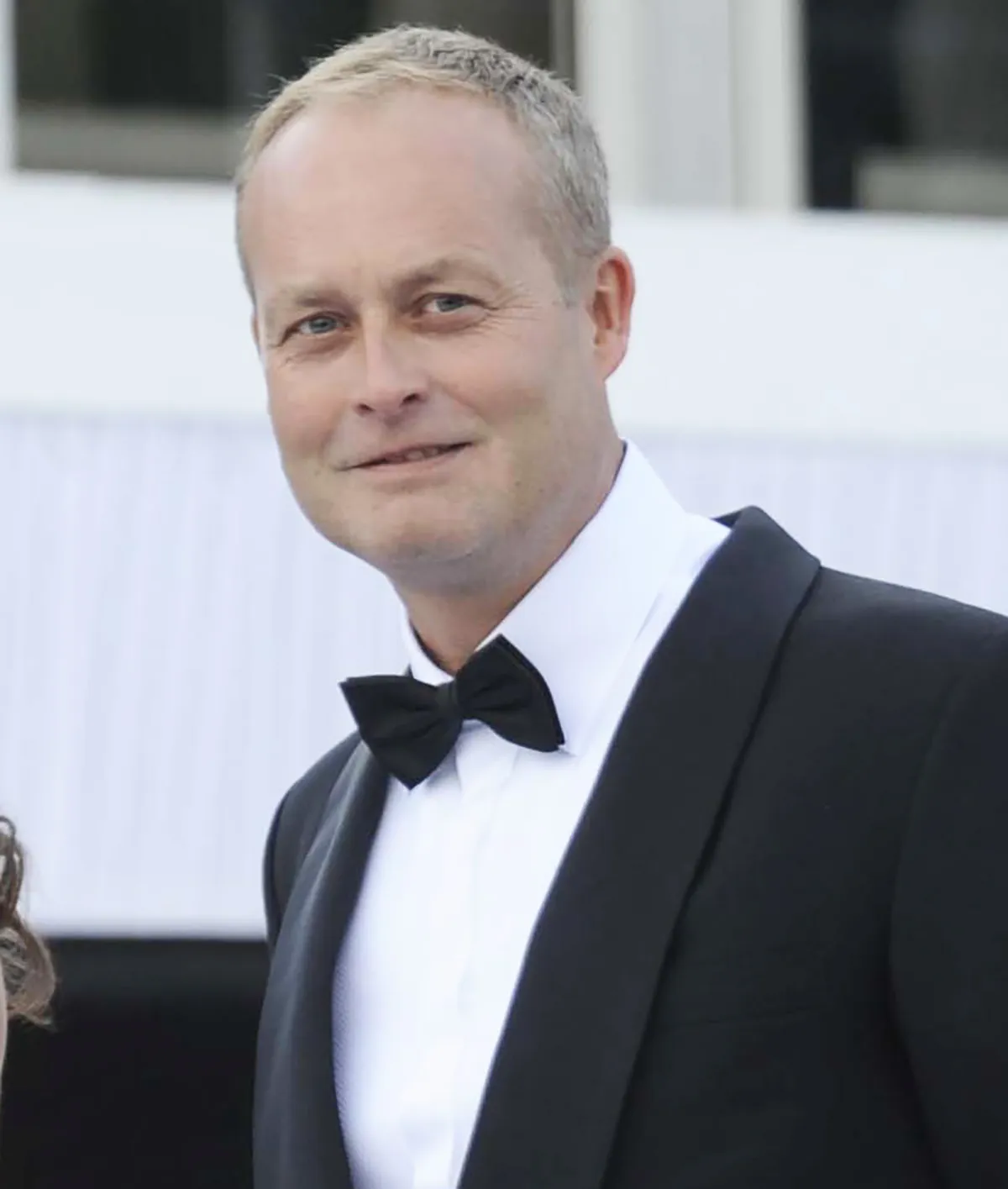 Ian Wace in a black tuxedo and bow tie, smiling.