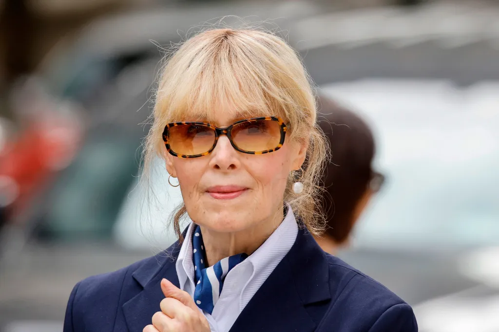 E. Jean Carroll wearing sunglasses and a navy blazer outside court.