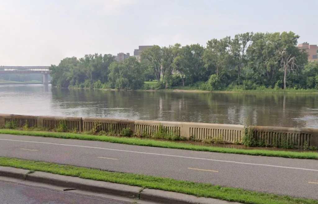 East River Flats Park with a paved path next to a short wall and a river.