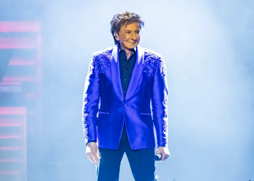 Barry Manilow performing on stage in a blue jacket.