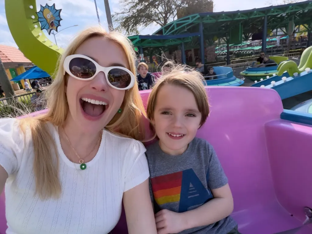 Emma Roberts and her son Rhodes smiling on a theme park ride.