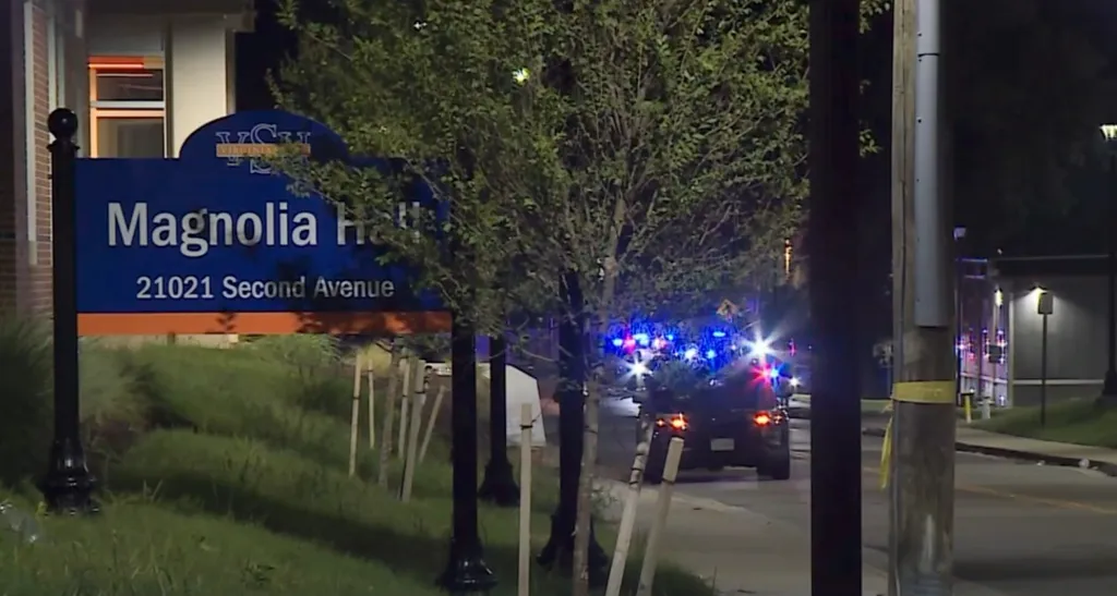 Police car with flashing lights near the Magnolia Hall sign at Virginia State University following a shooting.