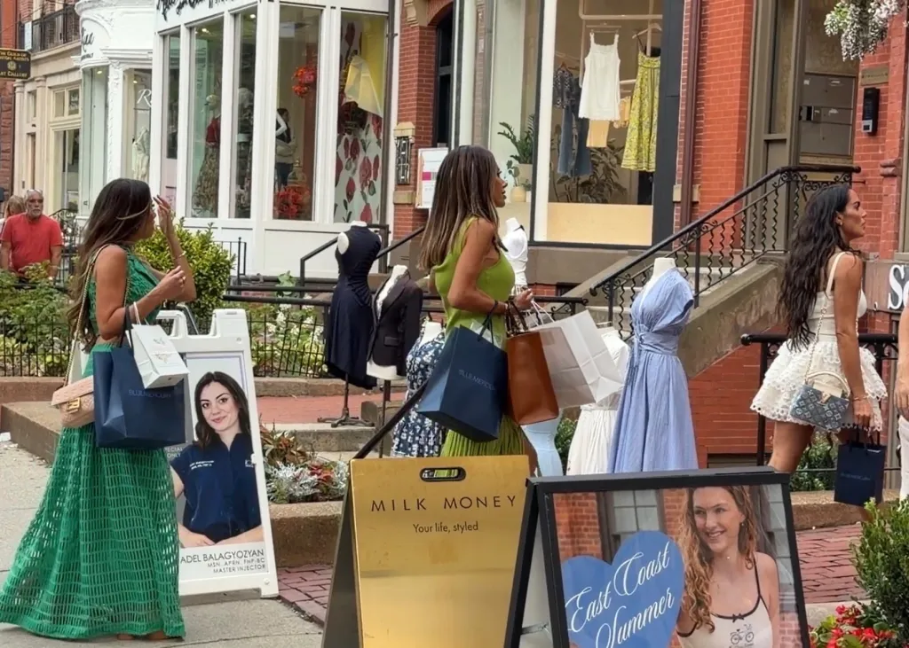 Rosie DiMare, Rulla Nehme Pontarelli, Alicia Carmody, Liz McGraw, Dolores Catania, and Ashley Iaconetti, cast members of The Real Housewives of Rhode Island, walk down a street with shopping bags past storefronts.
