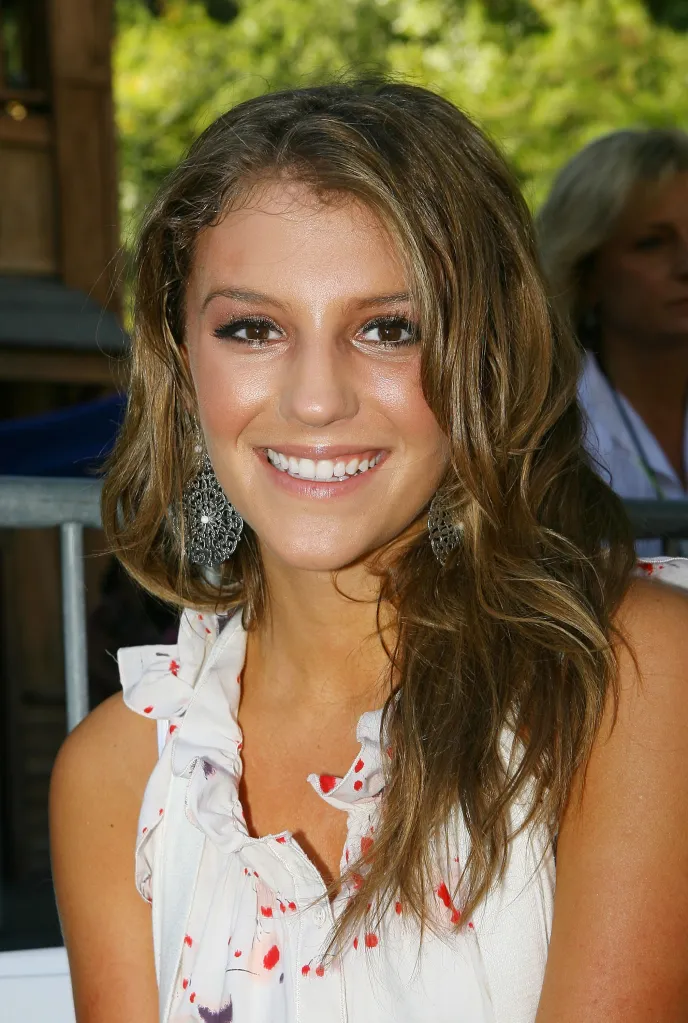 Singer Jordan Pruitt with long brunette hair, wearing pink lipstick and a white top with red and purple patterns.