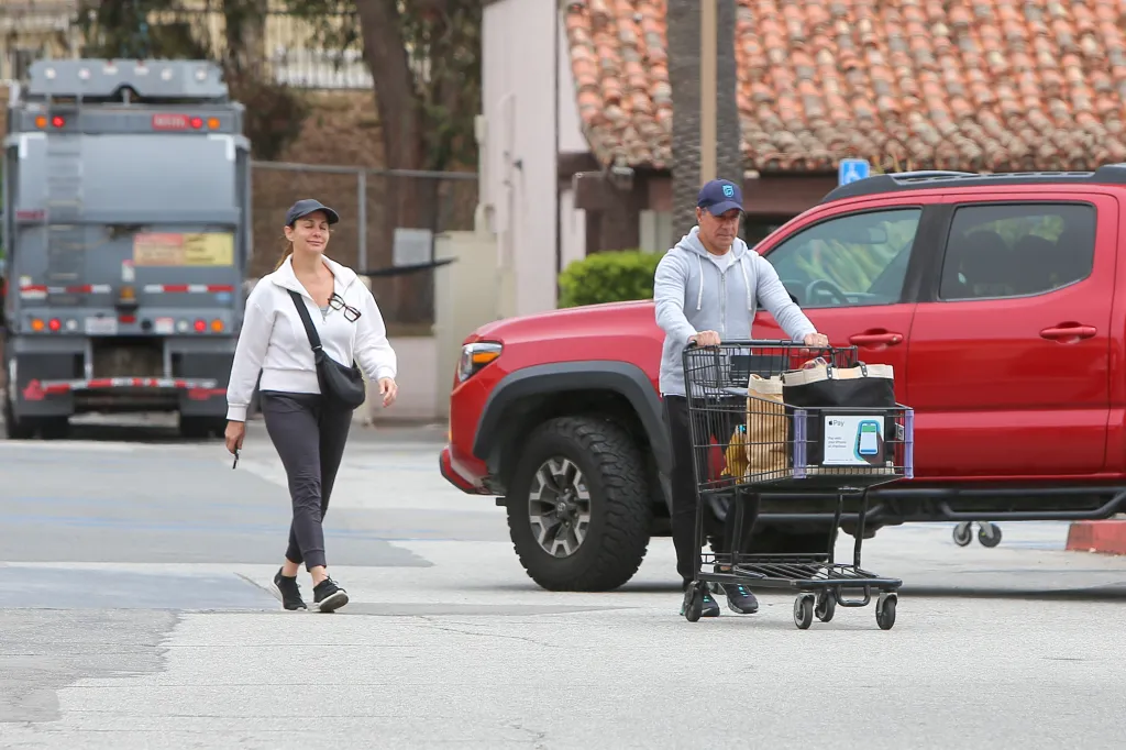 Alberto Carvalho pushing a shopping cart and his wife walking beside him outside a supermarket.