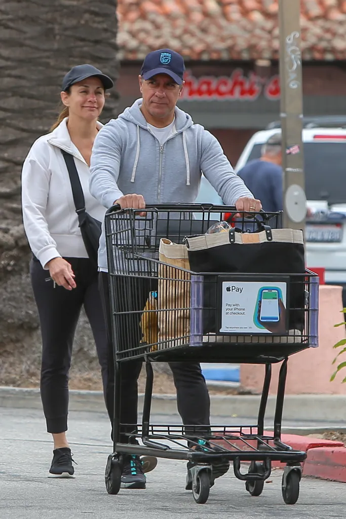 Alberto Carvalho pushing a shopping cart while walking with his wife.