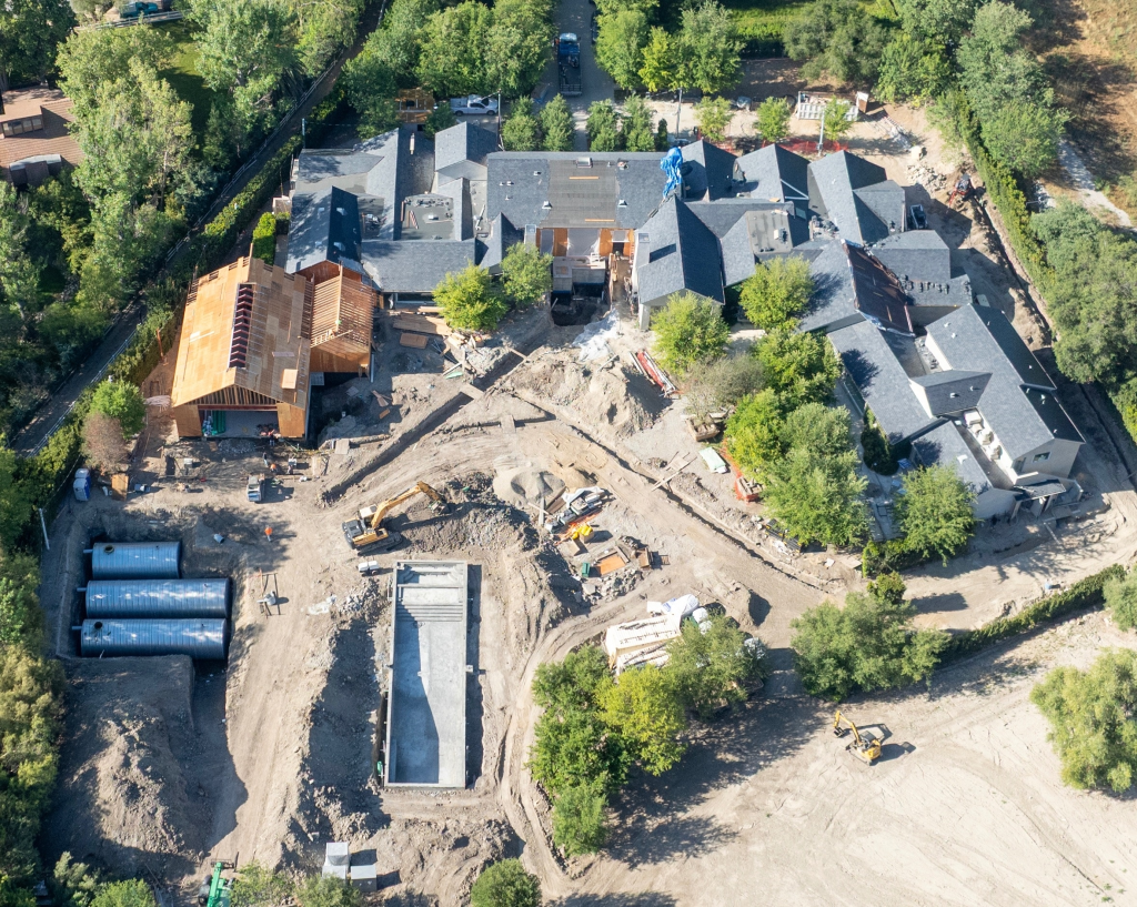 Aerial view of Kim Kardashian's Hidden Hills mega-mansion under construction, with a large house, swimming pool, and excavation machinery visible.