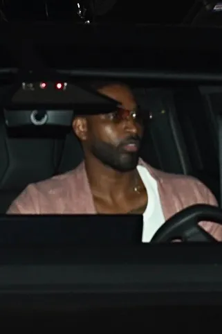 Tristan Thompson driving a Tesla Cybertruck, wearing a pink shirt and tinted sunglasses.